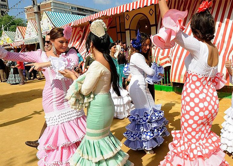 Women in colorful dresses dancing outdoors at a festival.