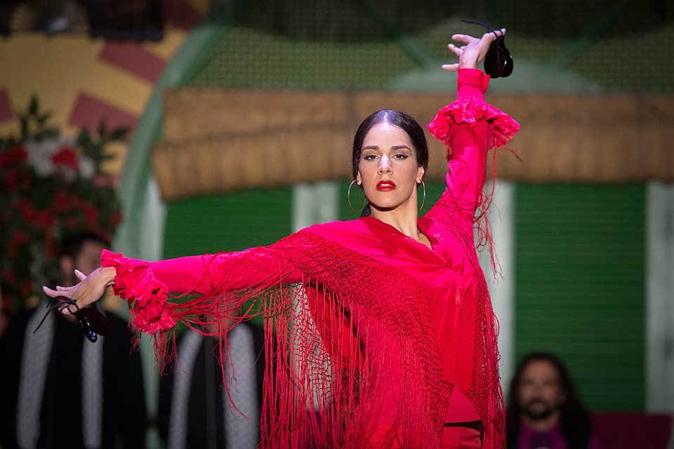 Woman dancing in a vibrant red outfit with arms gracefully extended.