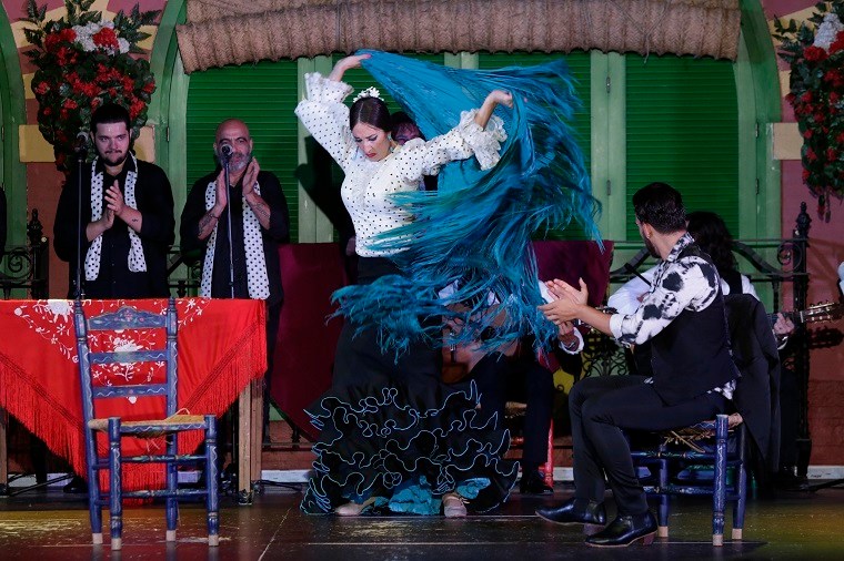 Flamenco dancer performing with musicians and colorful decor.