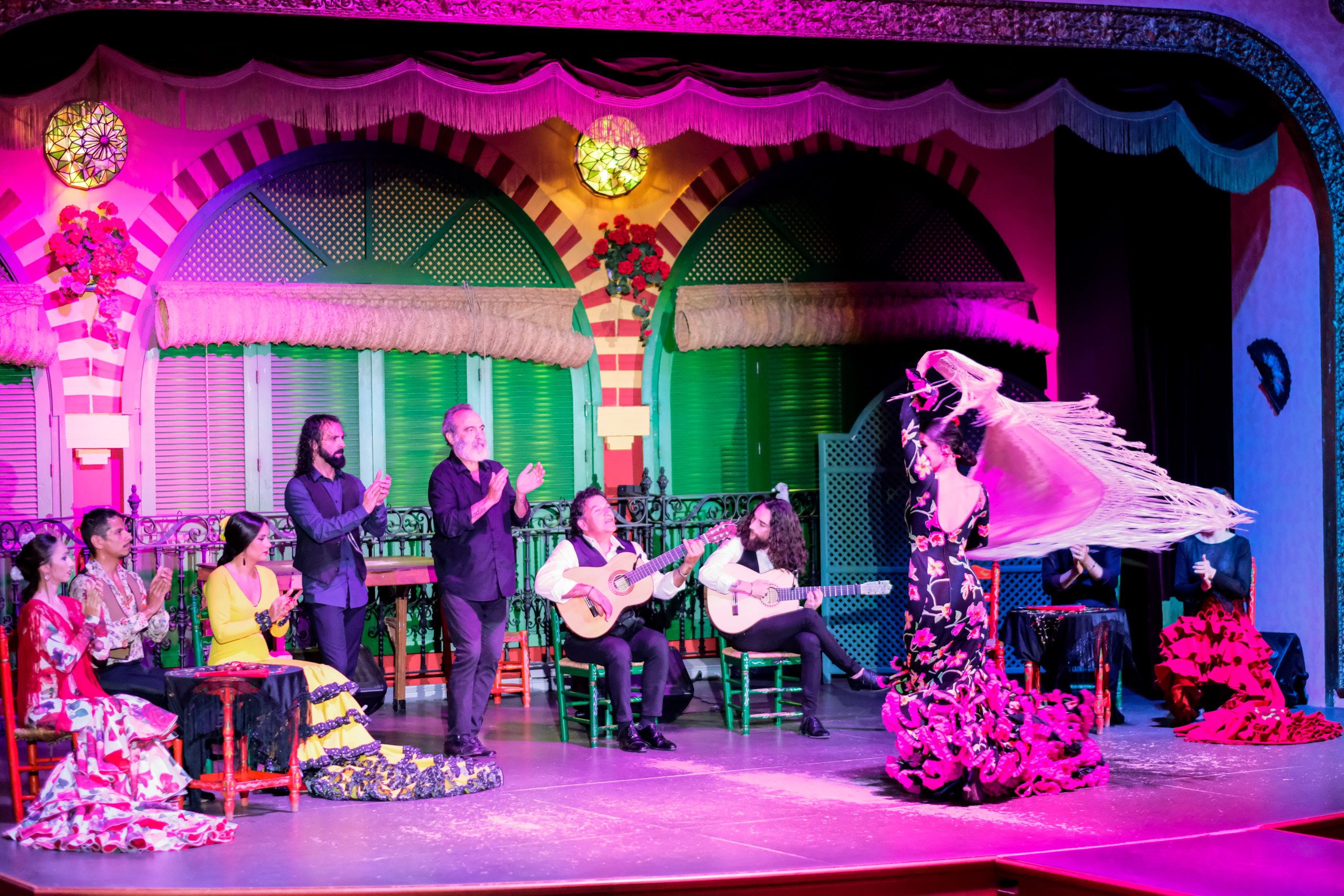 Flamenco performance with dancers and musicians on a vibrant stage.