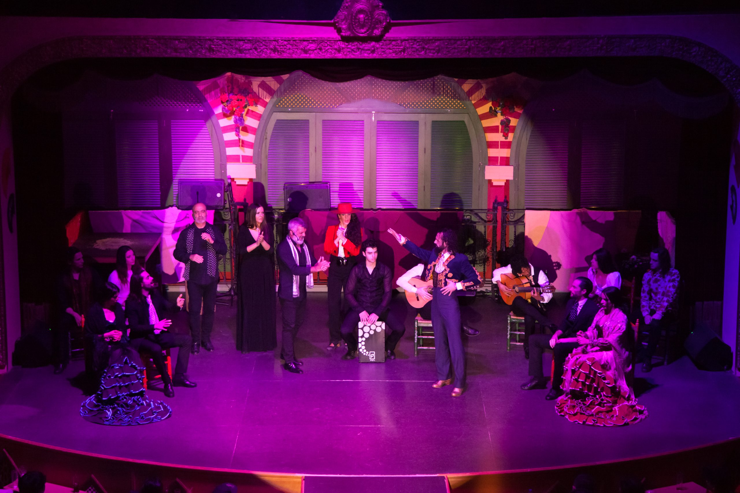 Stage performance with musicians and dancers under purple lighting.