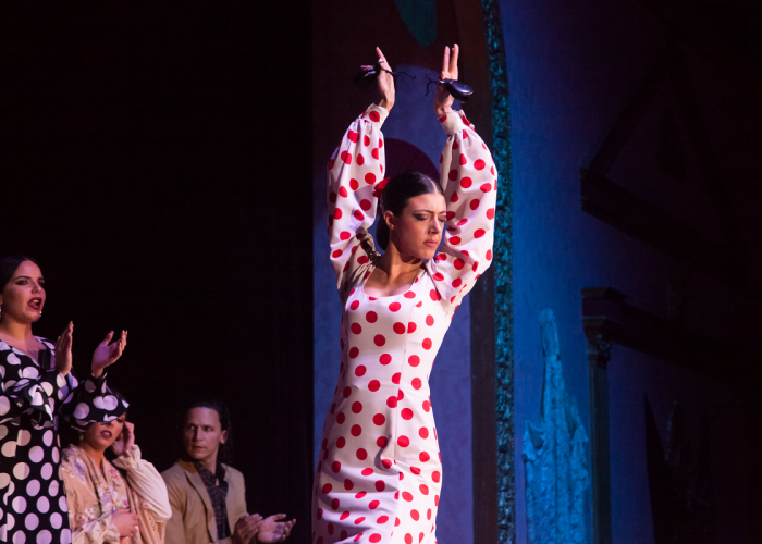 Dancer in polka dot dress performs on stage, people watch.