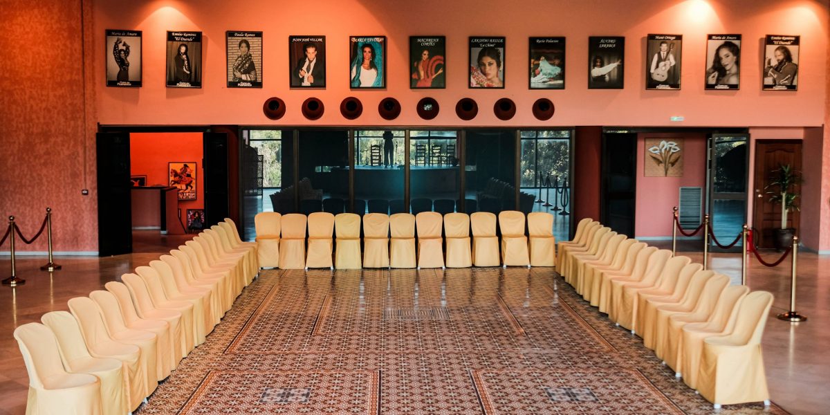 Room with chairs arranged in U-shape, portraits on pink walls above.