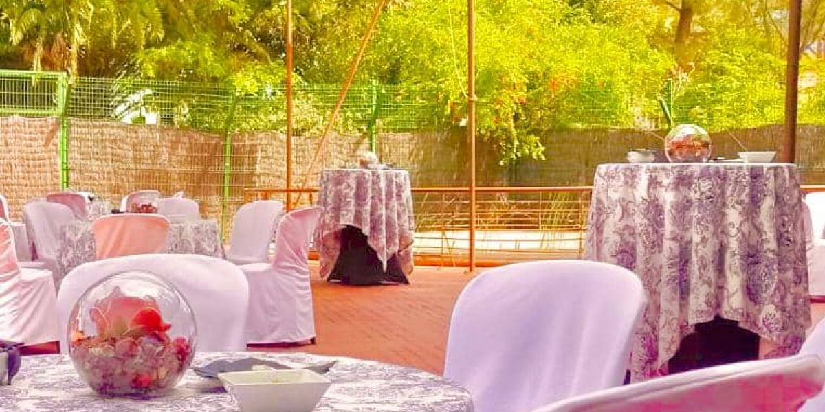 Outdoor setting with round tables, floral centerpieces, and white chairs.