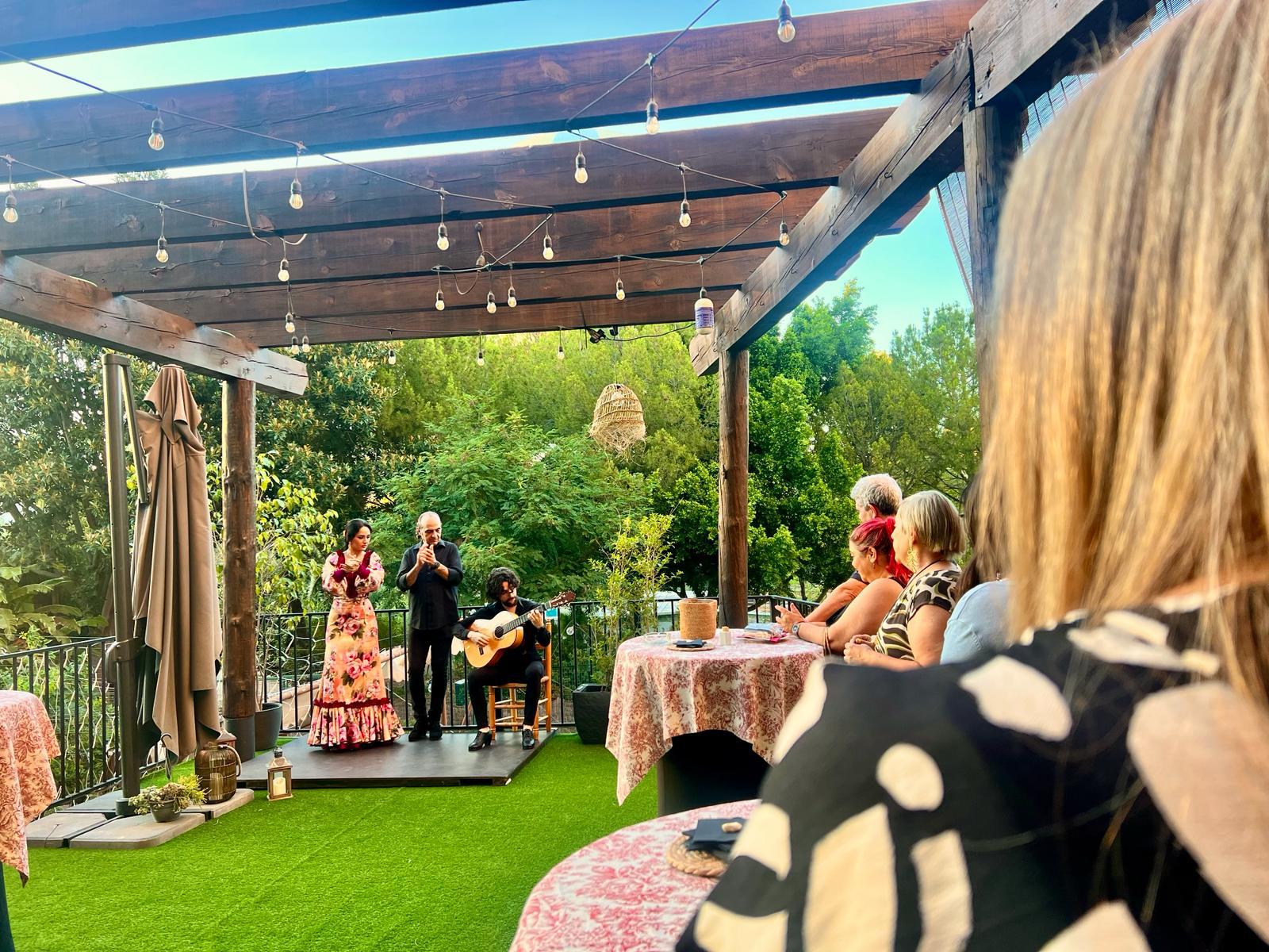 Outdoor performance with musicians and dancers on a covered patio, people watching.
