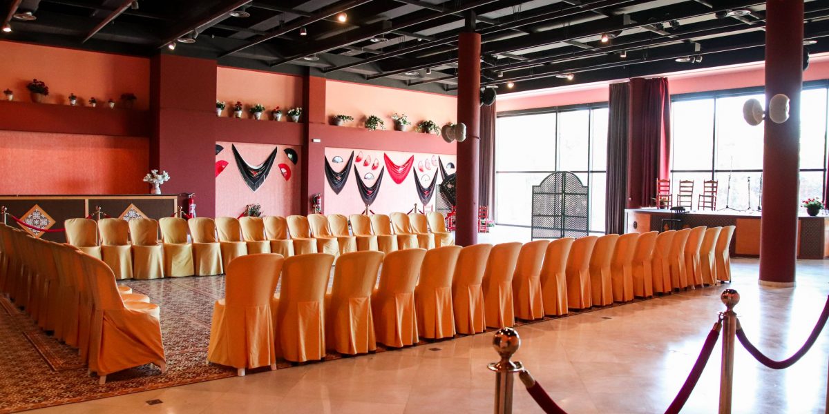 Elegant banquet hall with rows of orange chairs and festive wall decorations.