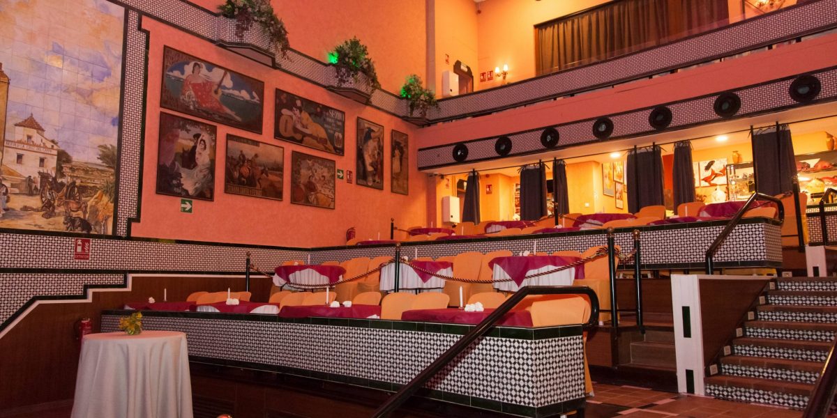 Interior of a theater or performance space with tiered seating and eclectic artwork on walls.