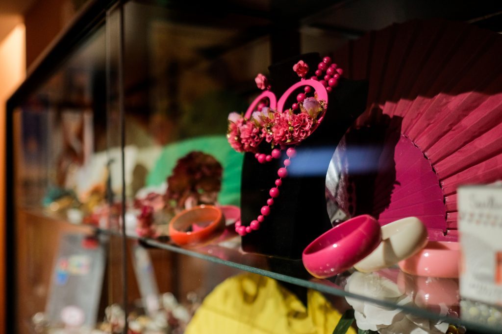 Display case with colorful fans, pink jewelry, and accessories.