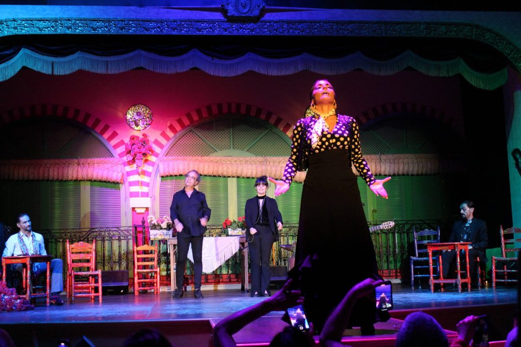 Performers on stage with colorful set and audience taking photos