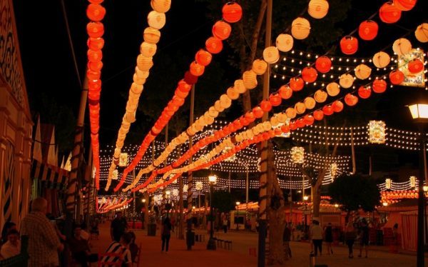 Colorful lanterns and string lights illuminate a lively night festival.