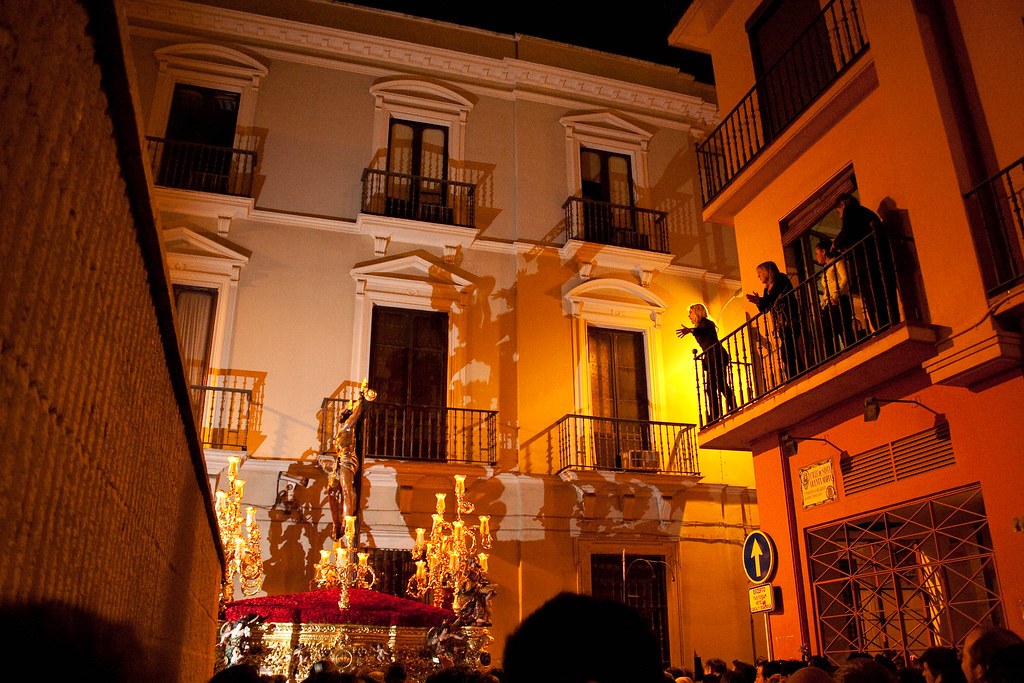 Night procession with religious statue and candelabra on a decorated float.