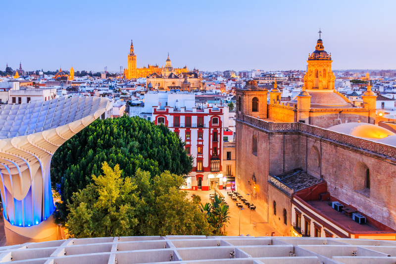 Panoramic view of Seville, Spain, with historic buildings and Metropol Parasol at sunset.
