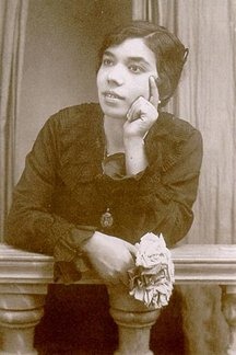 Vintage photo of a person leaning on a wooden railing, gazing thoughtfully, holding a flower.