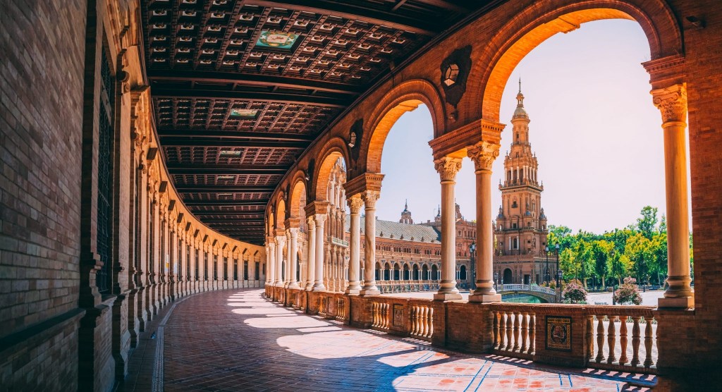 Sunlit arched walkway in Plaza de España, Seville.