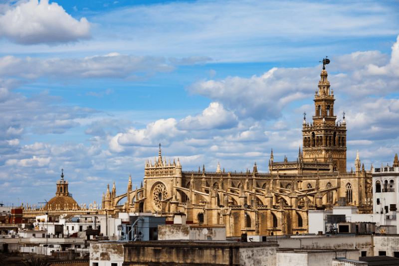Gothic cathedral with a bell tower under a partly cloudy sky.